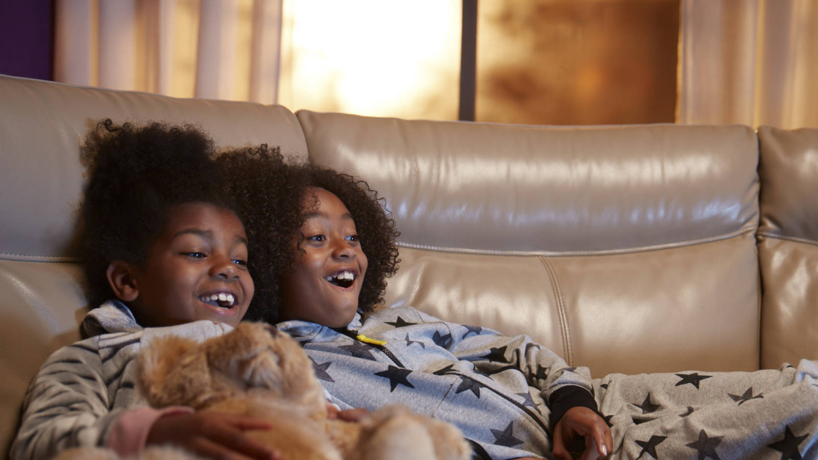 Children laughing on cream leather sofa