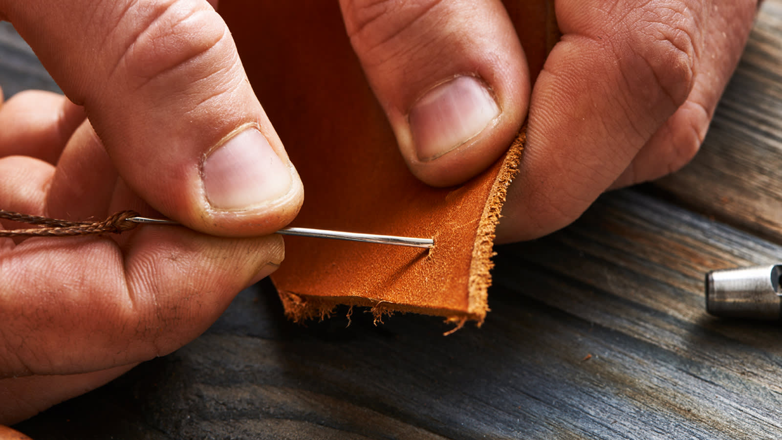 Man hand stitching leather