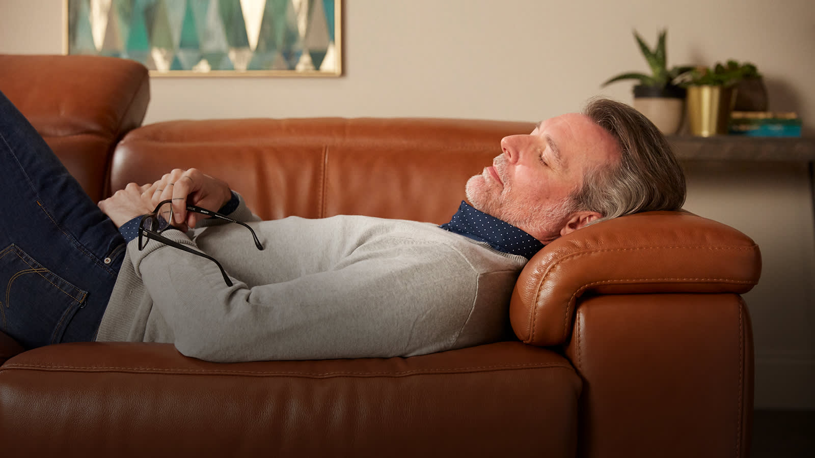 Man relaxing on brown leather sofa