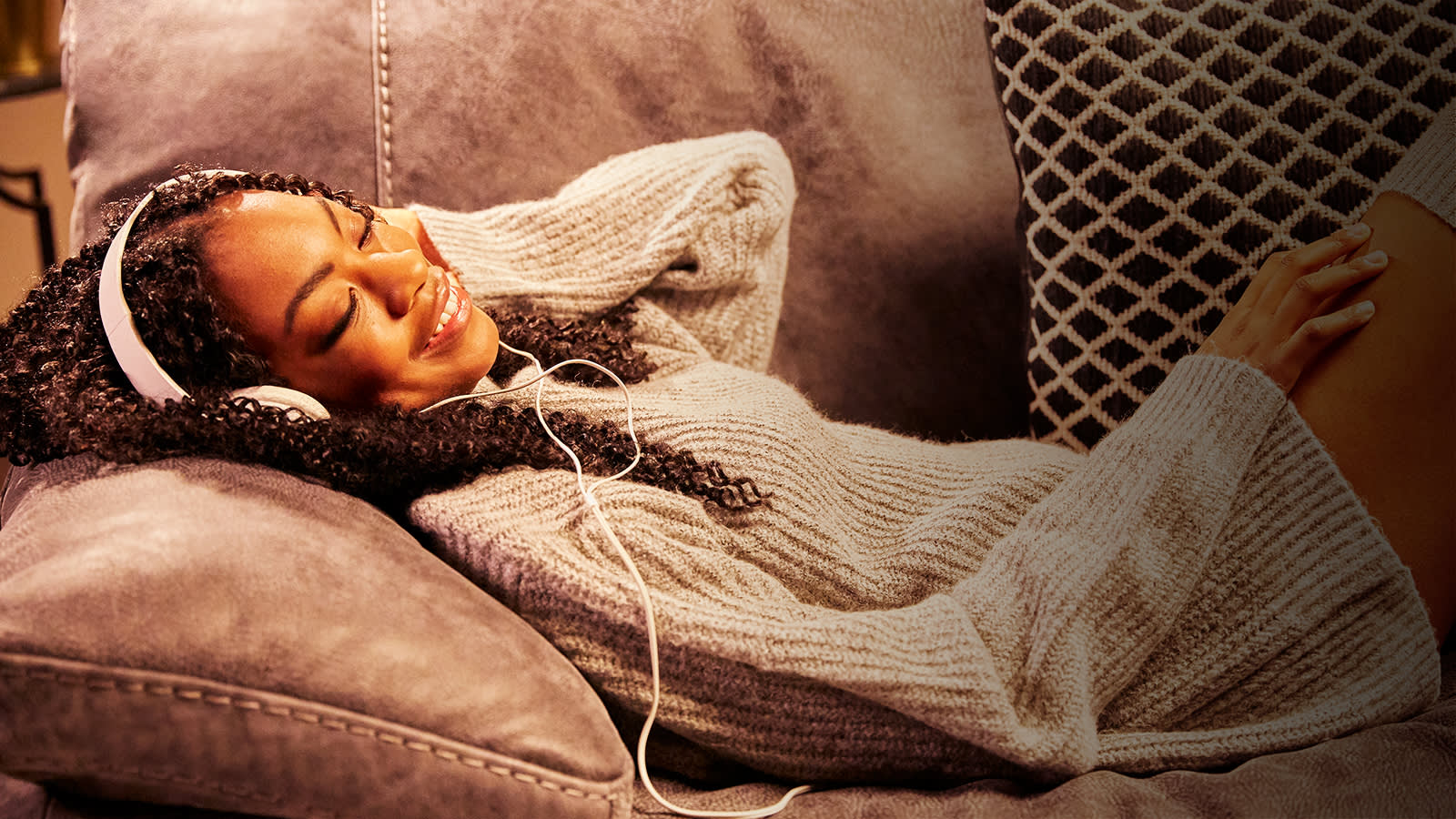 Woman relaxing on brown sofa listening to music