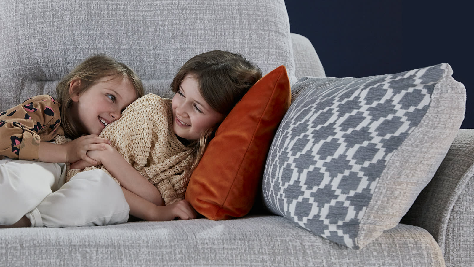 Children laughing of a grey fabric sofa