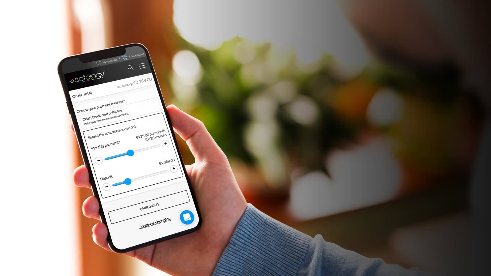 Man holding a mobile phone looking at the Sofology website