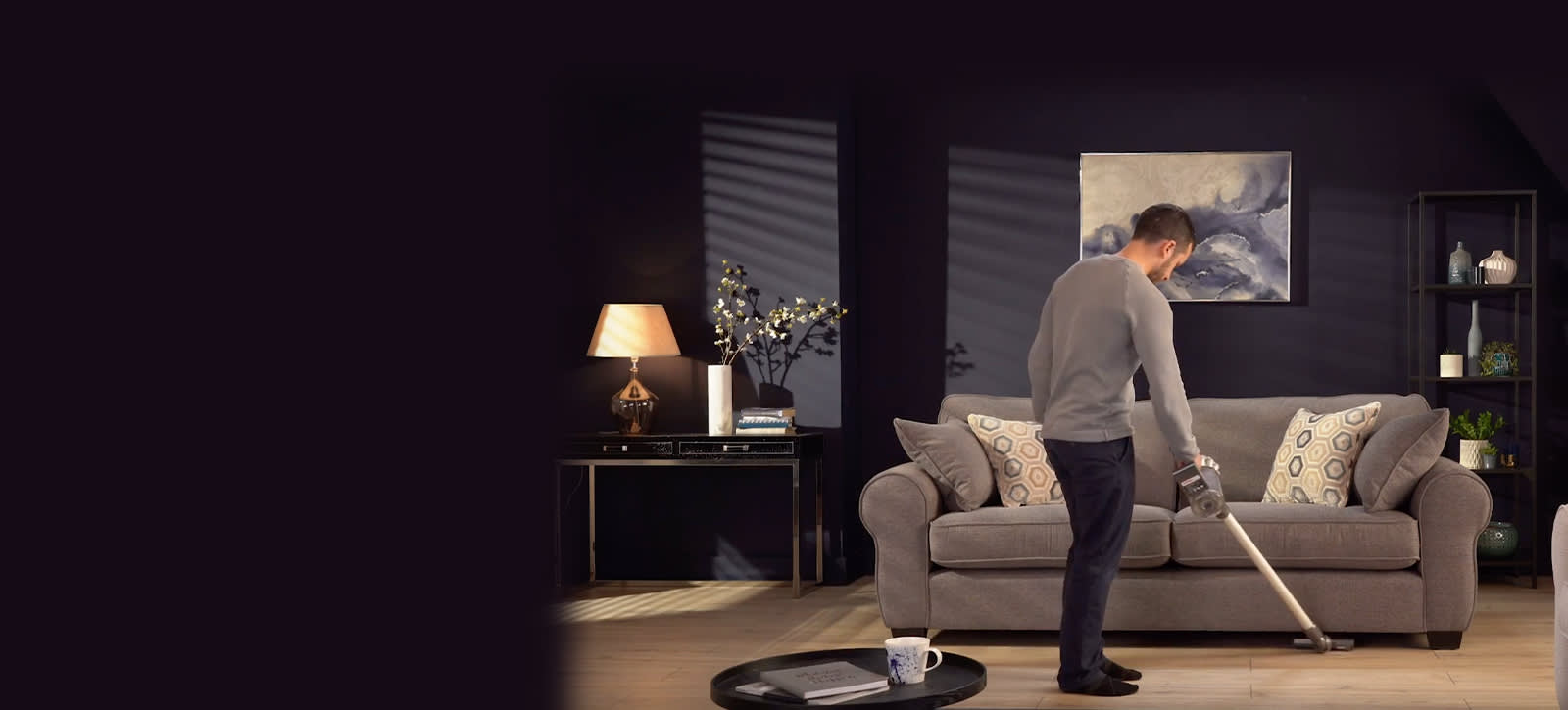Man vacuuming under sofa