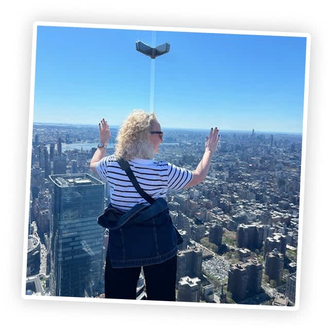 An image in a frame of a woman in the Rockefeller Center looking at the New York City skyline.